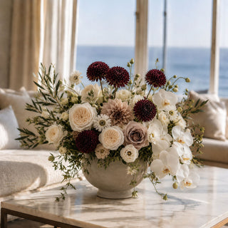 Full lush and luxurious floral arrangement featuring burgundy allium stems sitting on a marble table top 