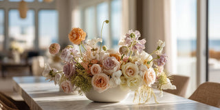 True Bloom Floral arrangement of mixed flowers on a table with a blurred indoor background