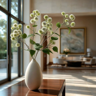 Real Touch White and Green Globe Amaranth stems styled in a tall neutral vase, adding airy movement, green filler texture, and year-round botanical softness to a modern floral arrangement.