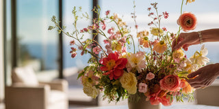 Hand arranging a colorful bouquet of flowers with a blurred outdoor background