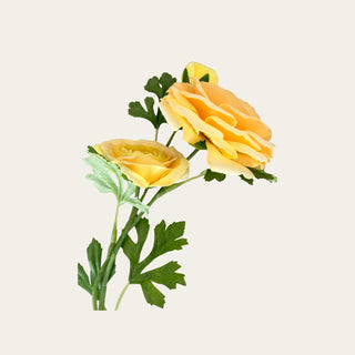 Close view of a yellow real touch triple bloom ranunculus stem showing layered buttery yellow petals, soft golden tones, and green faux foliage for refined floral styling.