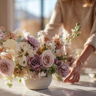 Woman arranging a luxury floral arrangement of  mixed florals on a table