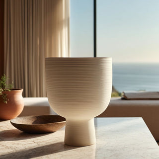 Wide mouth white ceramic vase on a marble table, styled in a modern coastal living room with neutral decor and ocean view